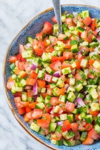 israeli salad in a blue bowl with spoon