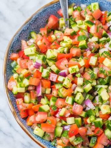 israeli salad in a blue bowl with spoon