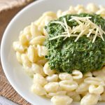 Portobello Mushroom, Kale and Spinach Puree on top of macaroni and cheese with parmesan garnish on white plate and rustic napkin