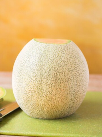 cantaloupe standing on cutting board with bottom and top sliced off