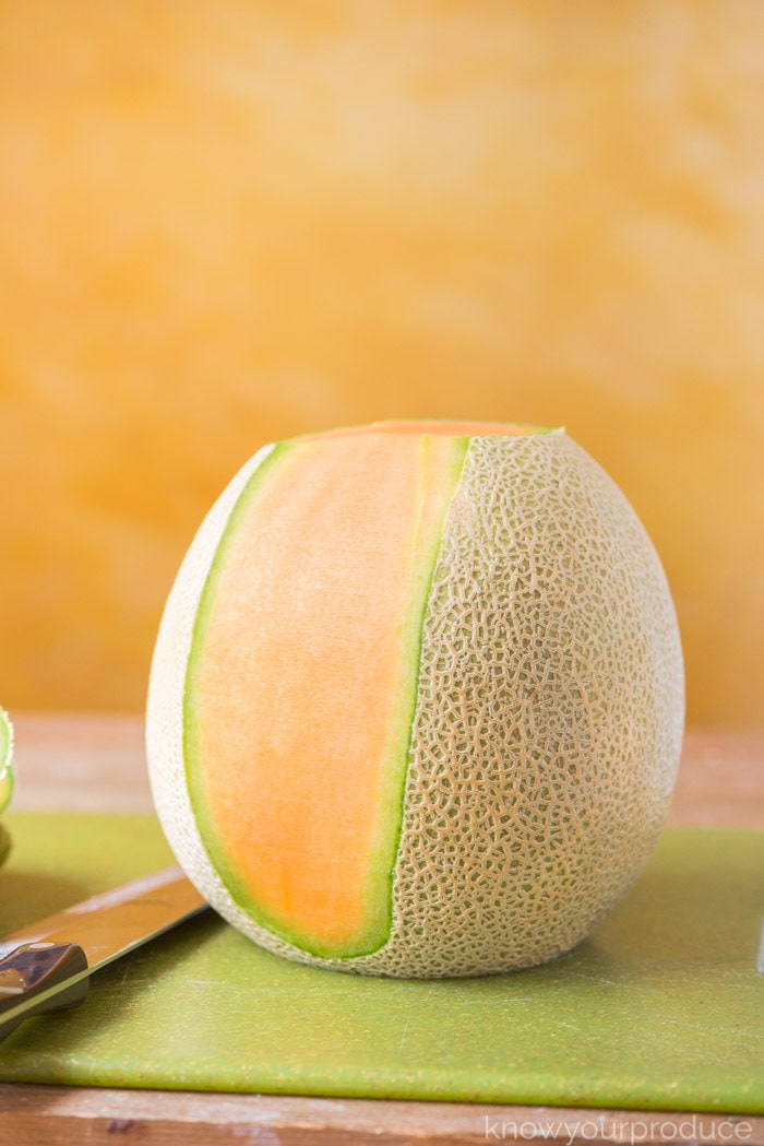 cantaloupe standing on a cutting board with rind partially removed