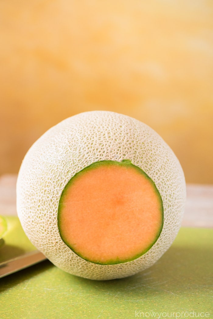 showing how to cut a cantaloupe cantaloupe on a cutting board with bottom sliced off