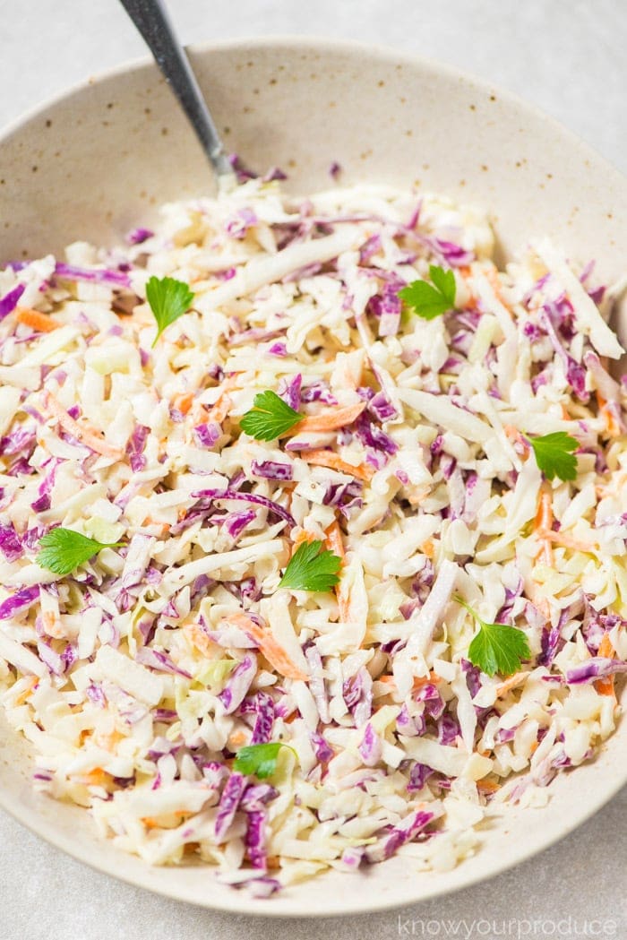 vegan coleslaw in a speckled low bowl with spoon