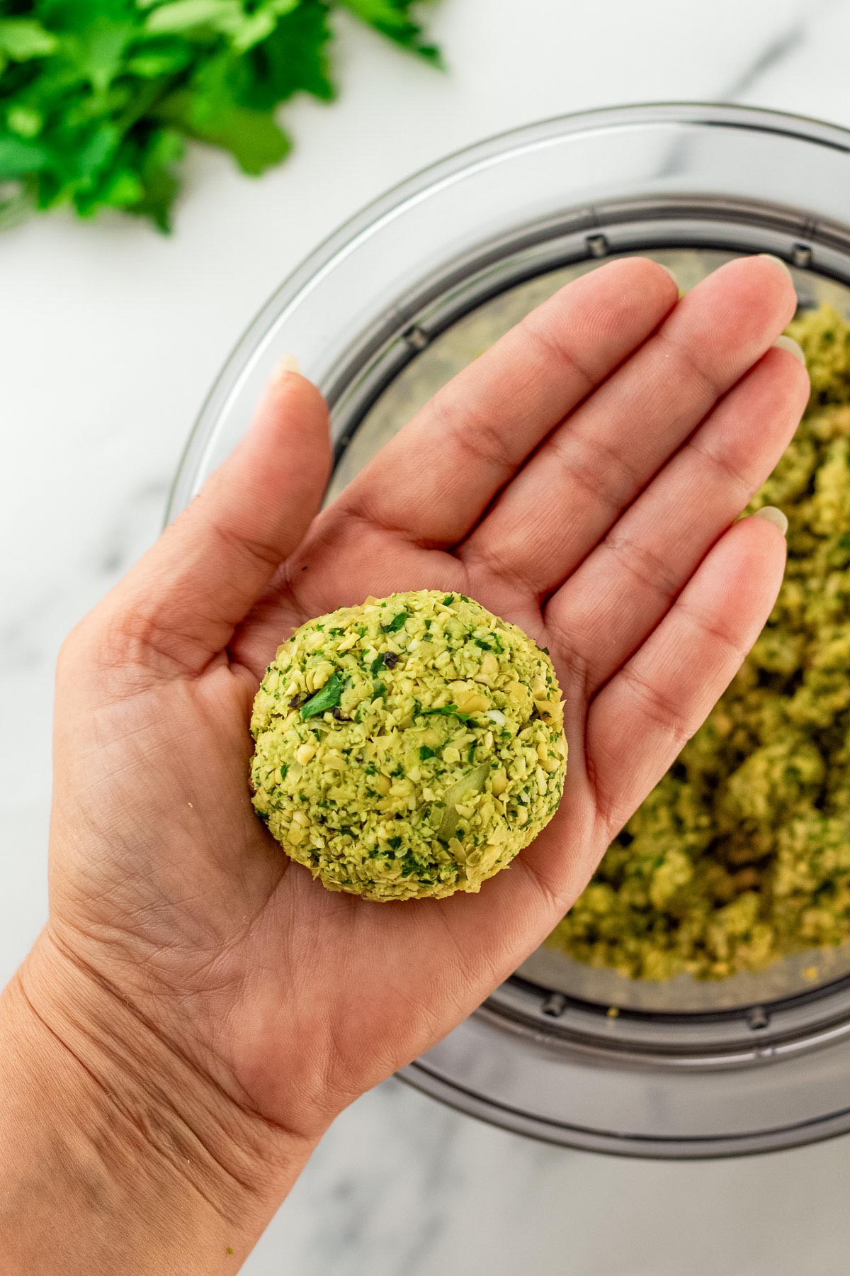 uncooked falafel shaped in palm of a woman's hand.