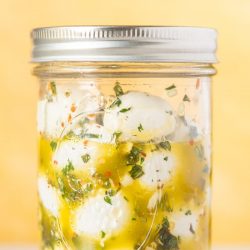 marinated mozzarella balls in a mason jar with olive oil and fresh herbs