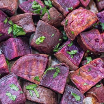 roasted purple sweet potatoes with parsley on a sheet pan