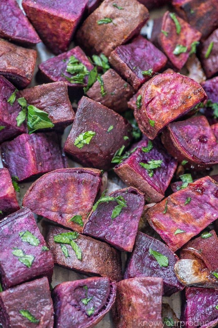 roasted purple sweet potatoes with parsley on a sheet pan