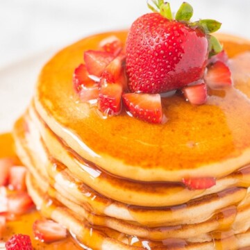 strawberry pancakes covered in maple syrup on a plate