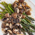 roasted asparagus and mushrooms with balsamic vinegar on a speckled plate