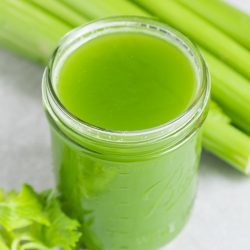 celery juice recipe in a mason jar with fresh celery in the background