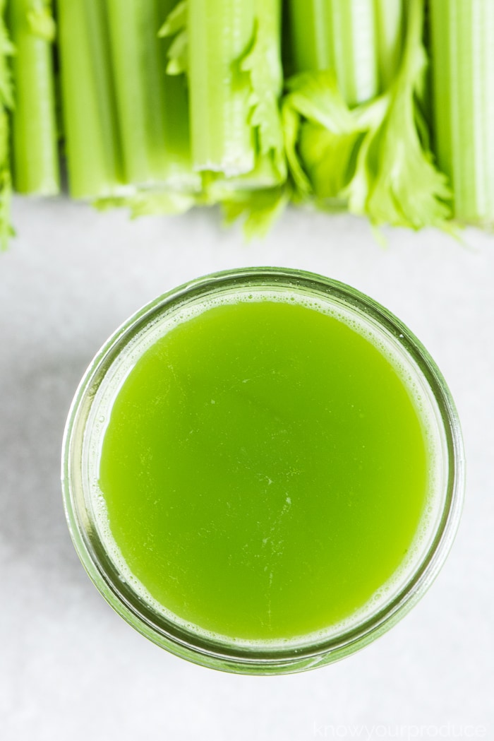 fresh celery juice in a mason jar with celery stalks on the top of photo
