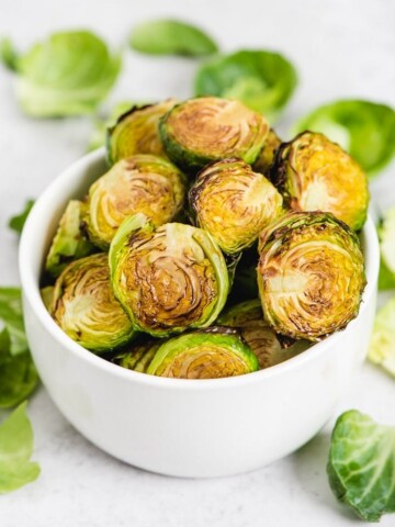 balsamic roasted brussels sprouts in a bowl with brussels sprout leaves scattered