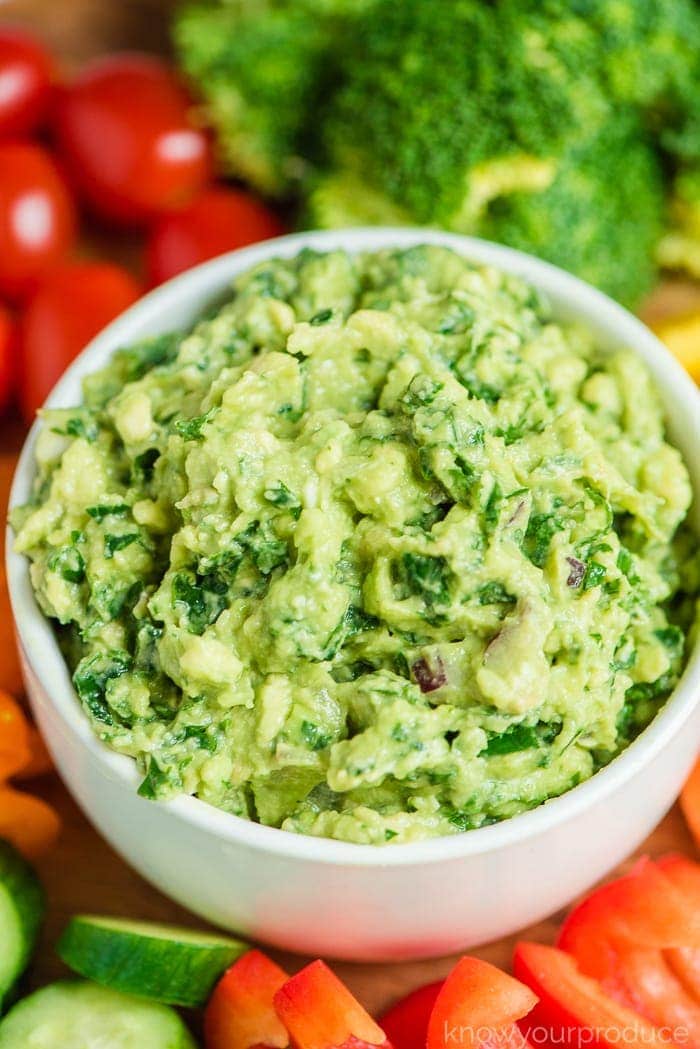 kale guacamole in a bowl with veggie platter