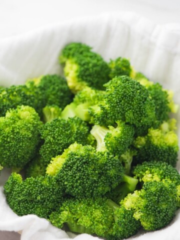 steamed broccoli in a bowl with a white cloth