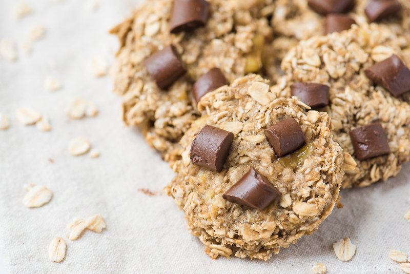 banana oatmeal chocolate chip cookies with scattered rolled oats on a cloth napkin