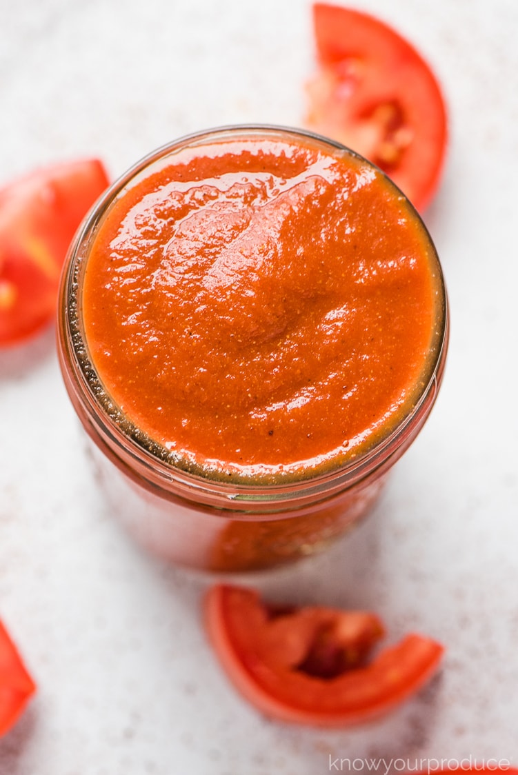 taco sauce in a glass jar with fresh tomatoes sliced on counter