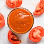 taco sauce in a mason jar with cut tomatoes sliced and halved on counter