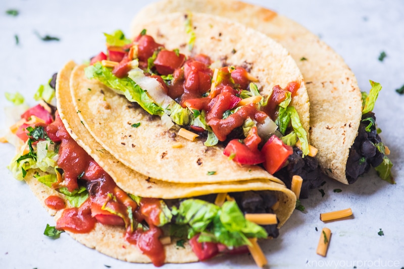 vegan tacos with black beans, lettuce, vegan cheese shreds, and fresh pico de gallo and taco sauce