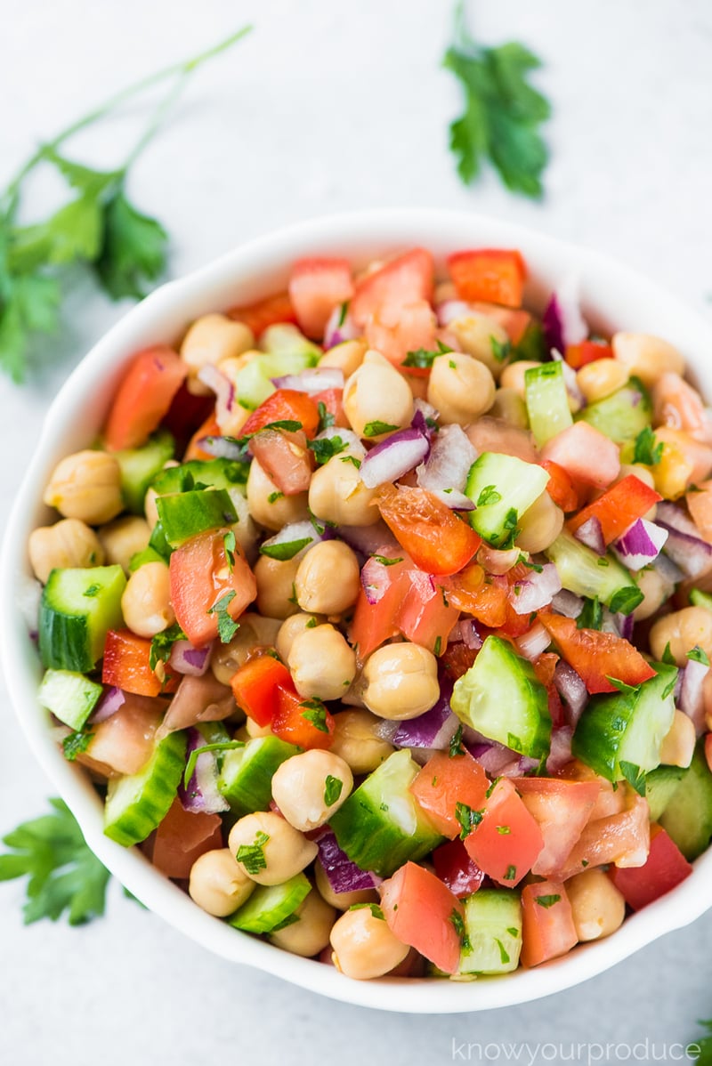 chickpea salad in a bowl with parsley scattered on the counter