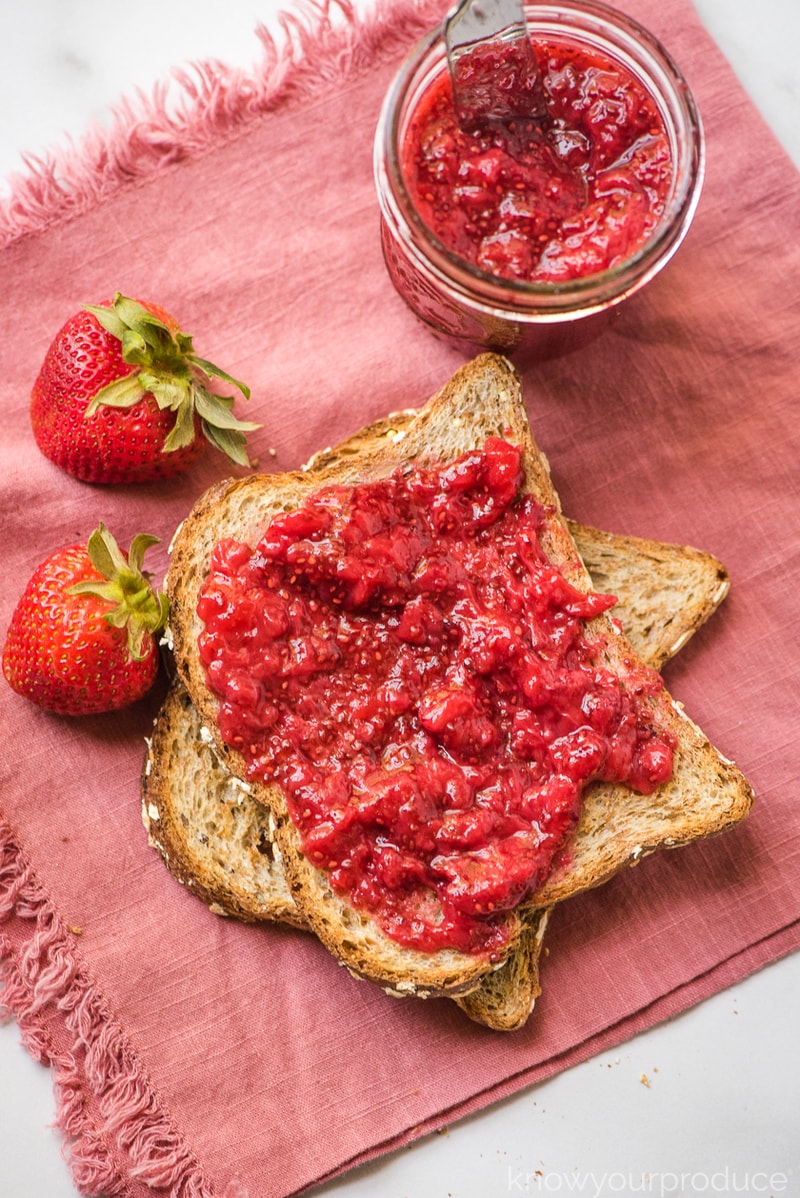 jam on toast and in mason jar on pink napkin with butter knife on plastic mason jar lid