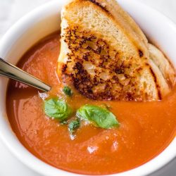 fresh tomato soup in a bowl with grilled cheese