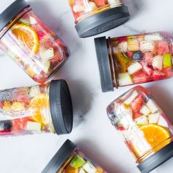 chopped fruit infused water in mason jars with plastic lids