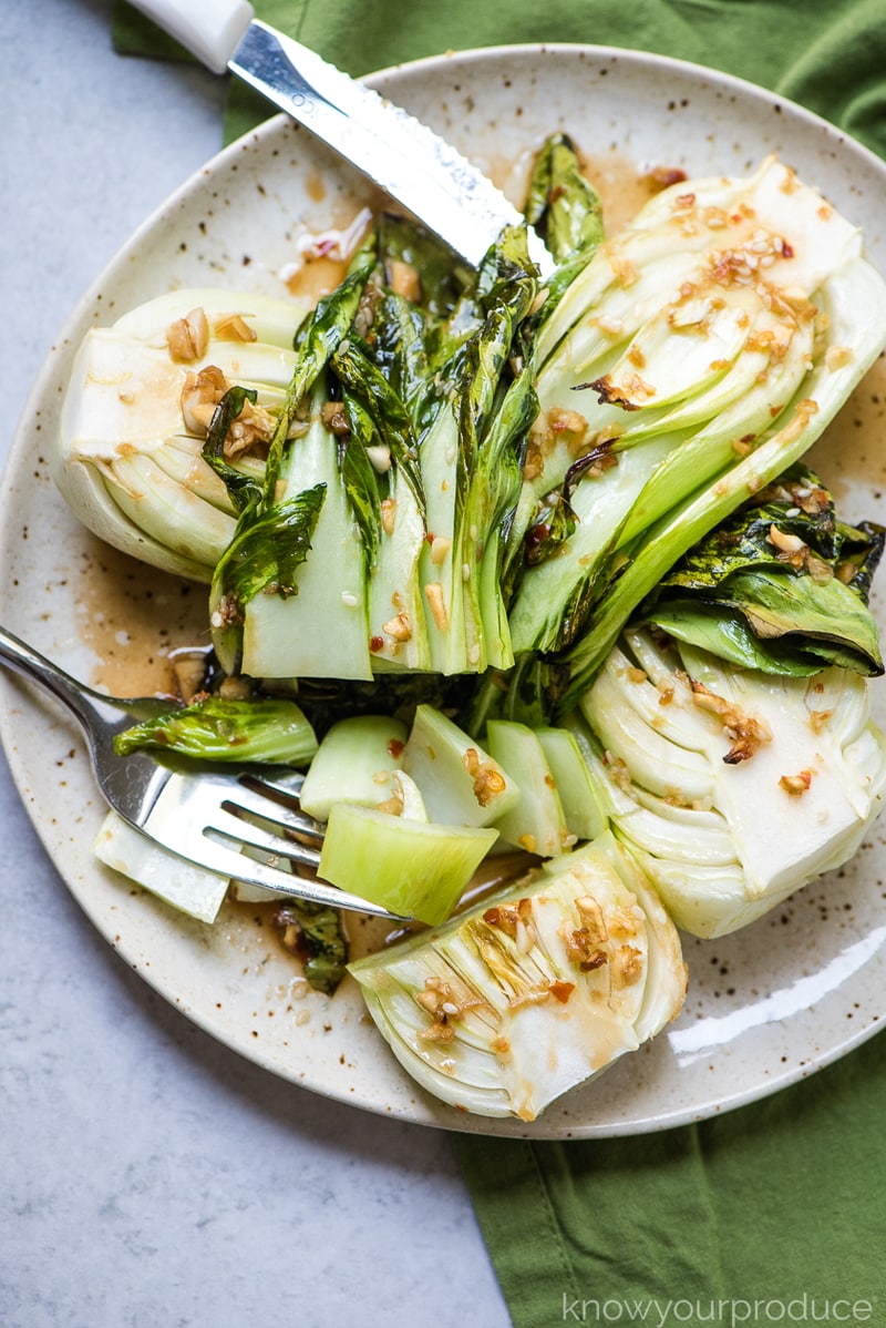 cooked boy choy on a plate cut with a fork