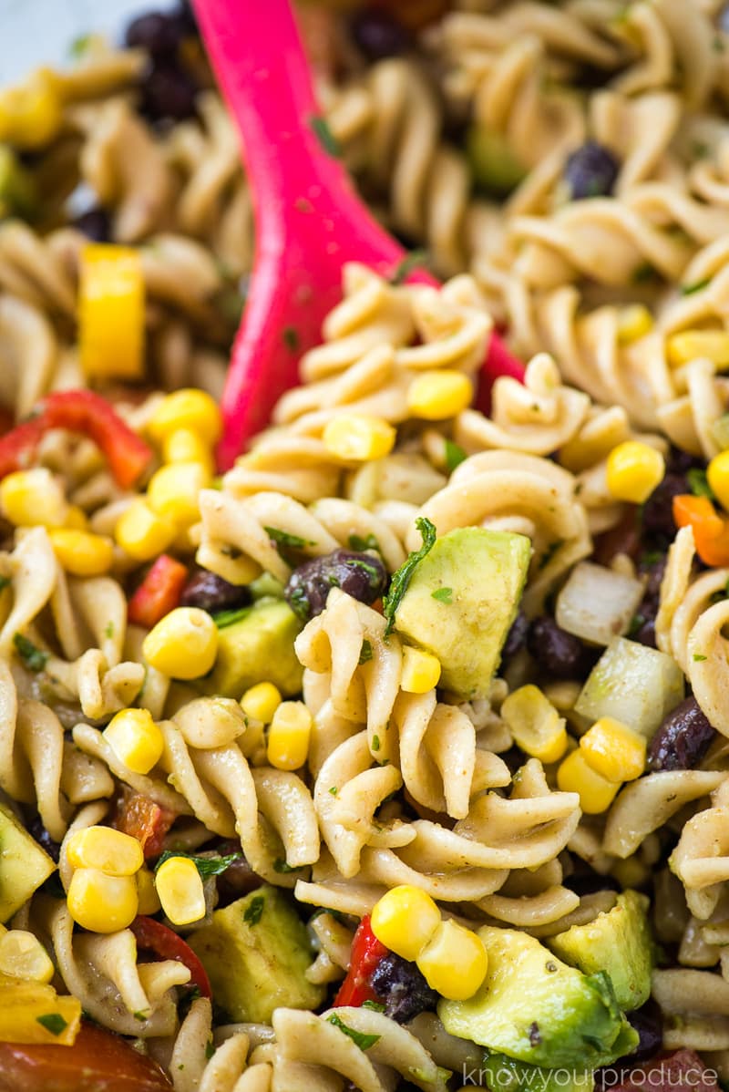 mexican pasta salad with whole wheat pasta in a bowl with pink spoon