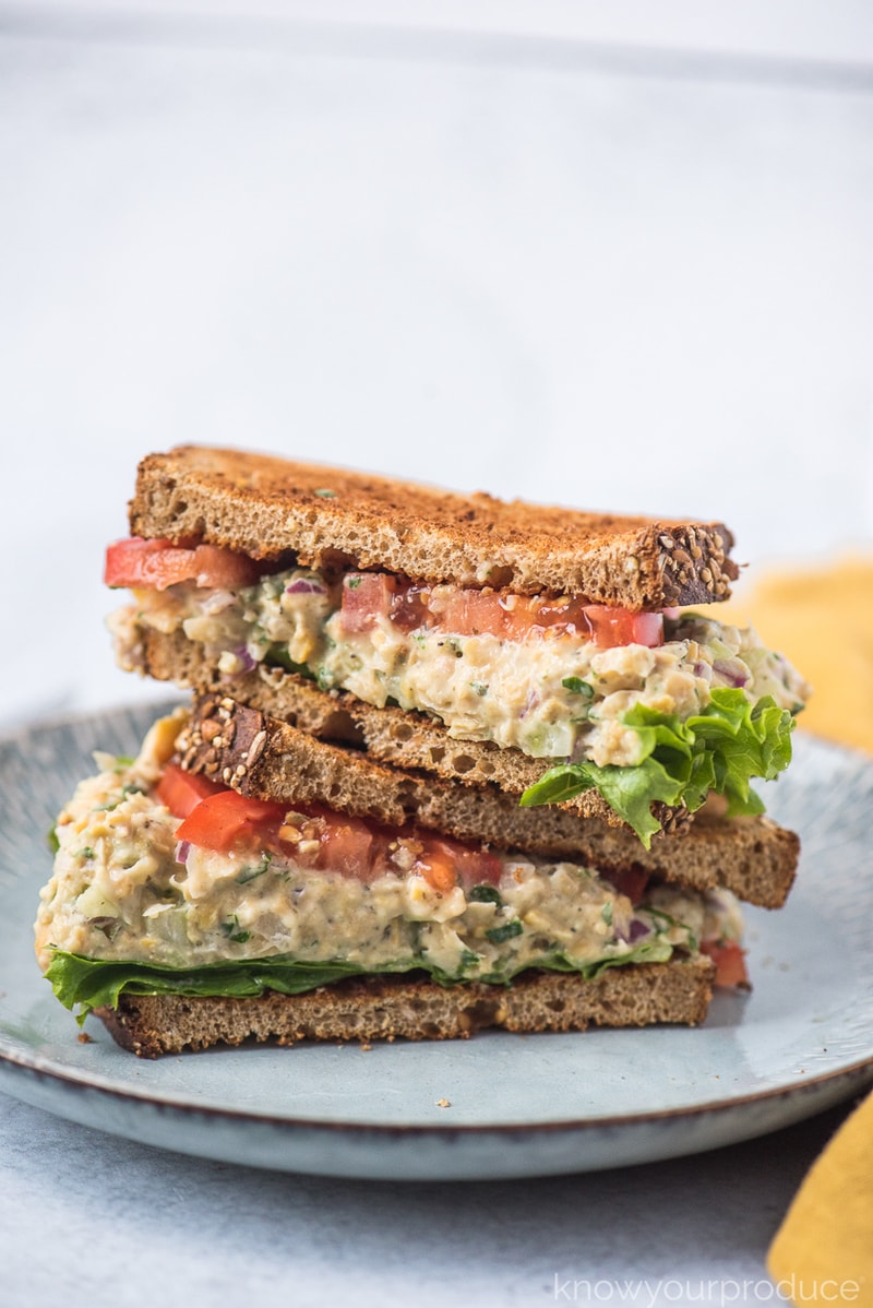 vegan tuna salad with chickpeas on wheat bread with lettuce and tomato on a light blue plate