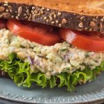 close up of vegan tuna salad on wheat bread with lettuce and tomatoes on a plate