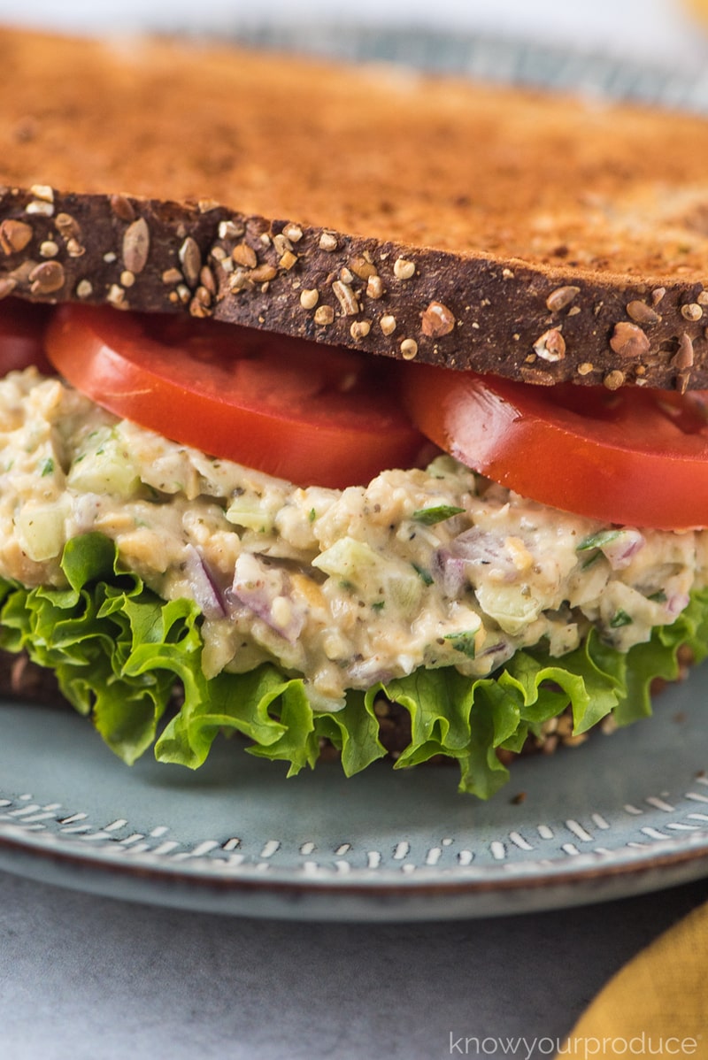 close up of vegan tuna salad on wheat bread with lettuce and tomatoes on a plate