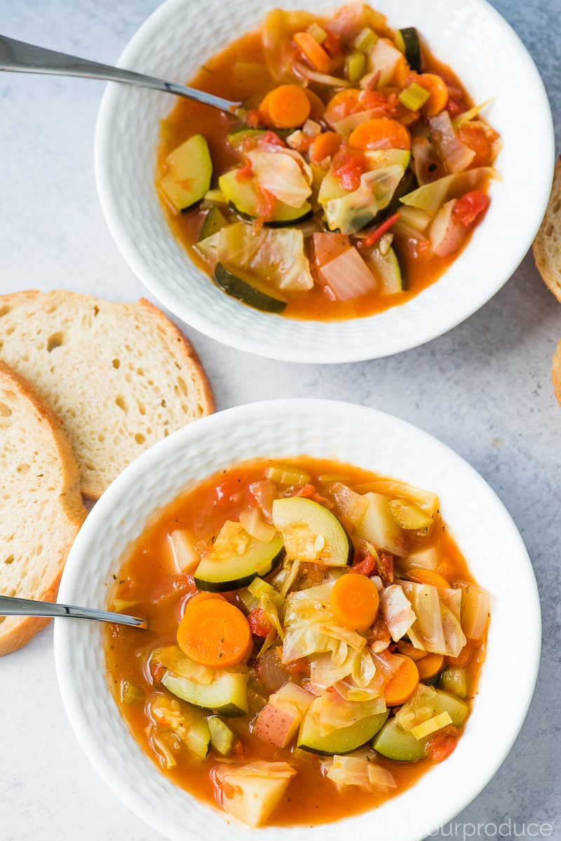 cabbage soup in a two low bowls with sourdough bread slices to the left side