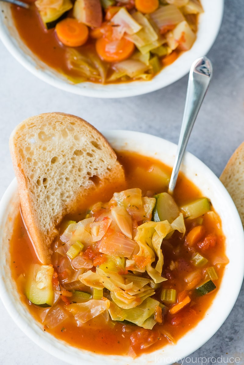 vegan cabbage soup in a bowl with bread and a spoon