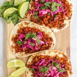 cauliflower tacos on a cutting board with wedges of lime