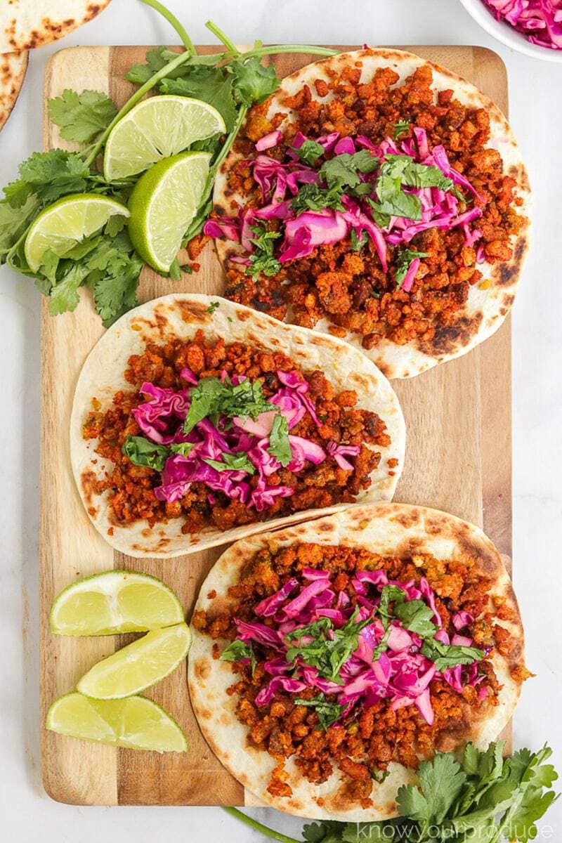 cauliflower tacos on a cutting board with wedges of lime