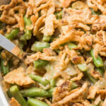 vegan green bean casserole with crispy green onions on top in white ceramic dish