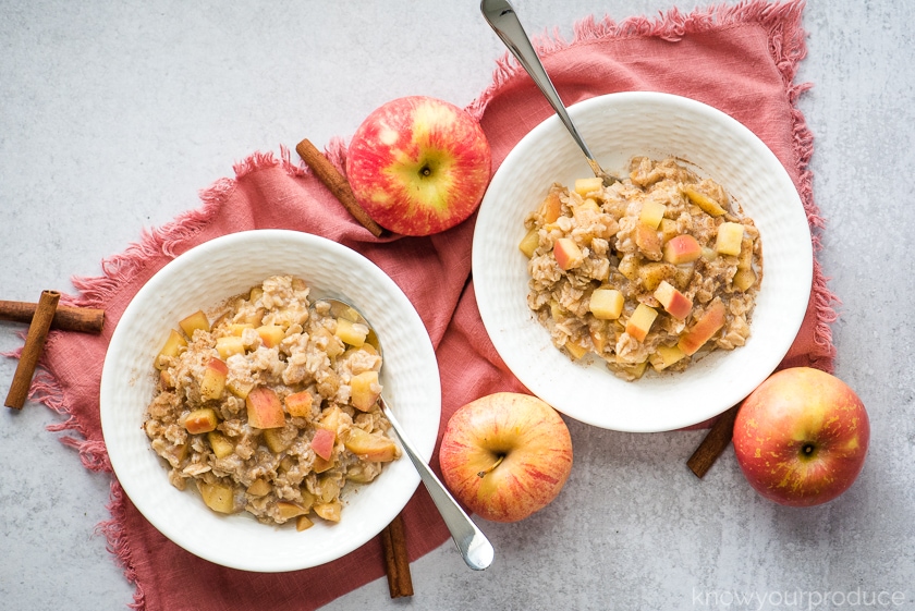 oatmeal breakfast in bowls with fresh apples to the sides on a pink napkin