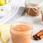 pear butter in a small mason jar with sliced pears to the left and bundled cinnamon sticks to the right