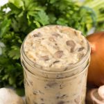 condensed cream of mushroom soup in a mason jar with mushrooms garlic onion and parsley around it