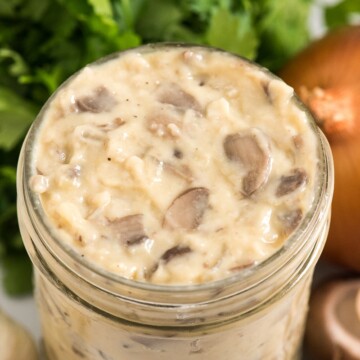 condensed cream of mushroom soup in a mason jar with mushrooms garlic onion and parsley around it