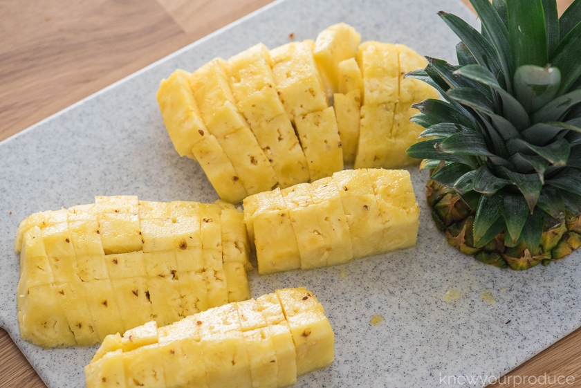 fresh cut pineapple chunks on a cutting board with top to the right