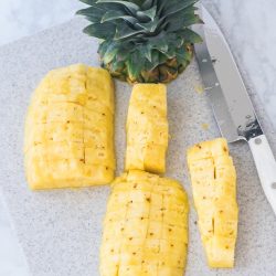 how to cut pineapple on a cutting board with pineapple top and cutco chef knife to the right