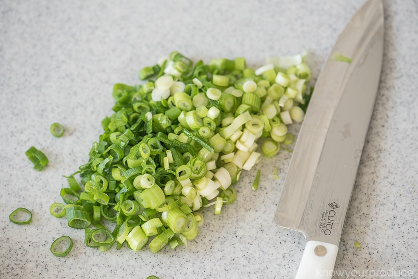 sliced scallions on a cutting board with cutco knife