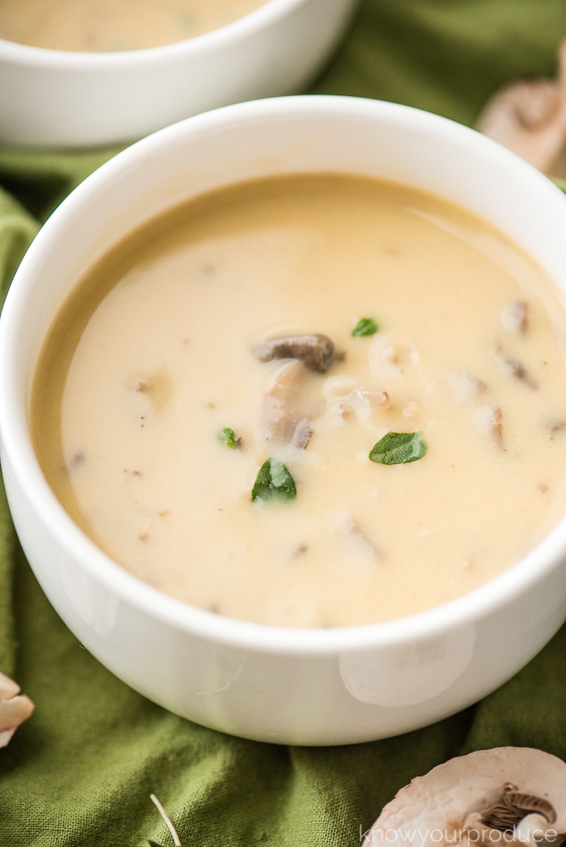 vegan cream of mushroom soup in a white bowl with thyme garnish 