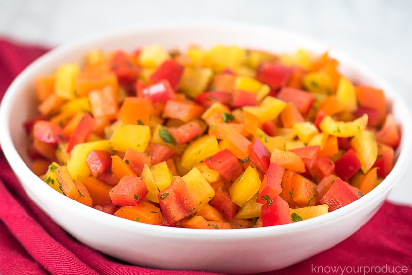 colorful pepper salad in a white bowl with red napkin underneath