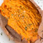 fork mashed air fryer sweet potato seasoned with kosher salt and parsley on a white plate