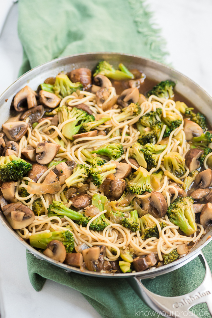 broccoli mushroom stir fry with lo mein in a stainless steal pan on a green napkin