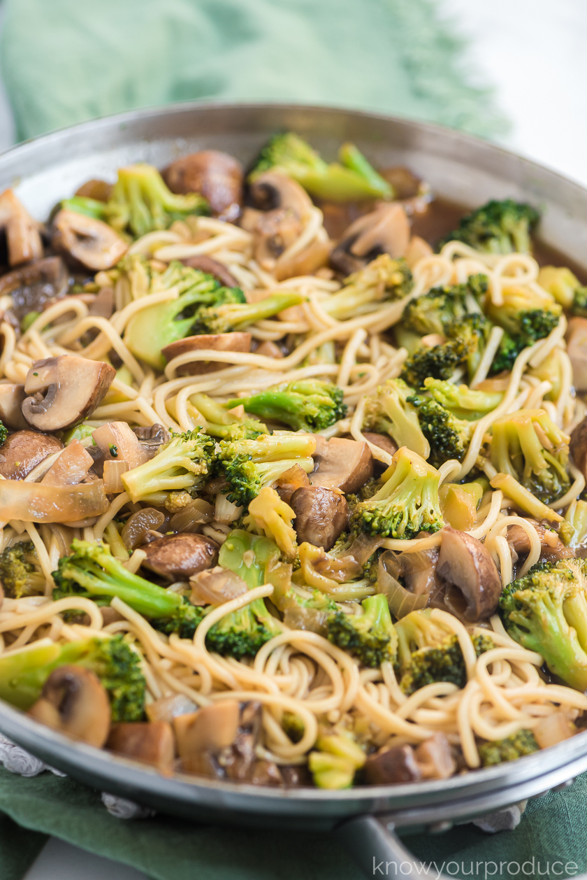 broccoli mushroom stir fry with lo mein in a stainless steal pan on a green napkin