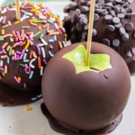 chocolate covered apples on a plate with a green napkin underneath
