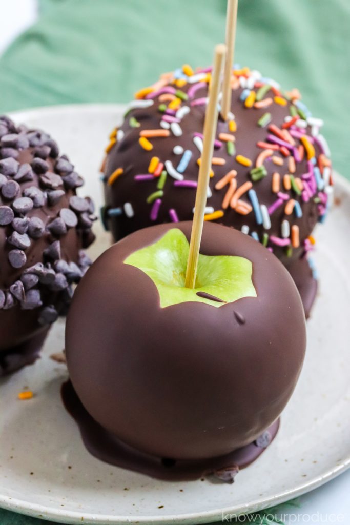 chocolate covered apples on a plate with a green napkin underneath